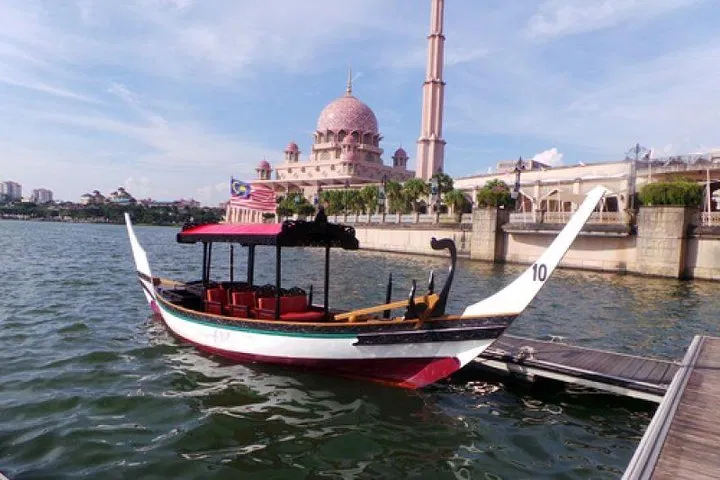 A traditional covered perahu moored at the jetty on Putrajaya Lake, the Putra Mosque behind it